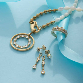 Ohrhänger BOBBY gold mit Ring und Perlen auf blauem Untergrund