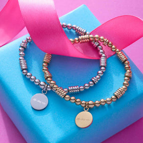 Stretch Armband ELISABETH gold auf blauem Untergrund mit rosafarbener Schleife