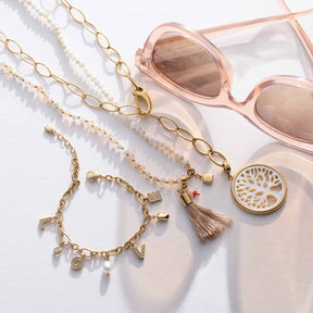 Halskette DONNA mit Glasperlen, Goldkette und Charm-Anhängern, Sonnenbrillen und Deko-Objekt auf weißem Untergrund