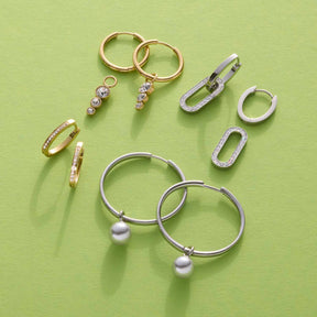 Schmuckkollektion auf grünem Hintergrund: goldene und silberne Ringe, Ohrringe und Anhänger