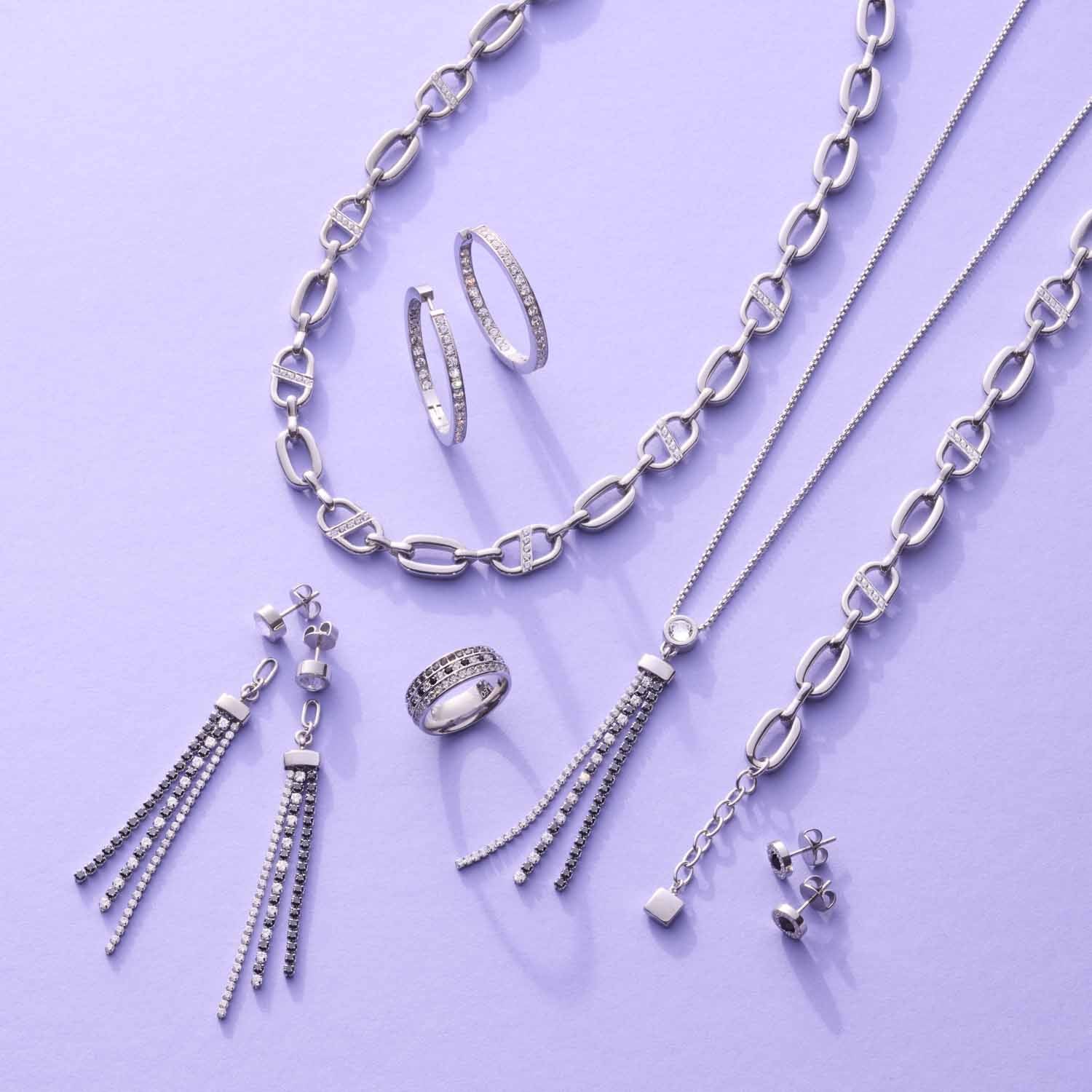 Silberner Schmuck der Serie JASMIN auf violettem Hintergrund: Creolen, Ketten, Ohrringe und Ring