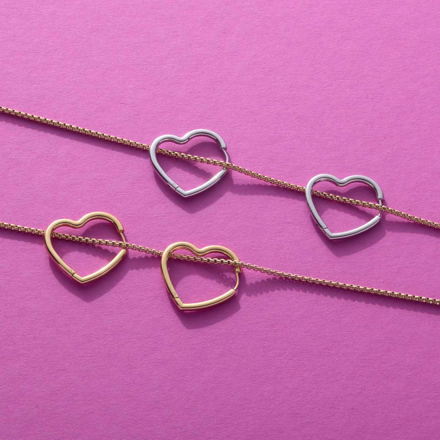 Creole LULU in Silber und Gold auf rosa Hintergrund, vier herzförmige Anhänger an feinen Ketten