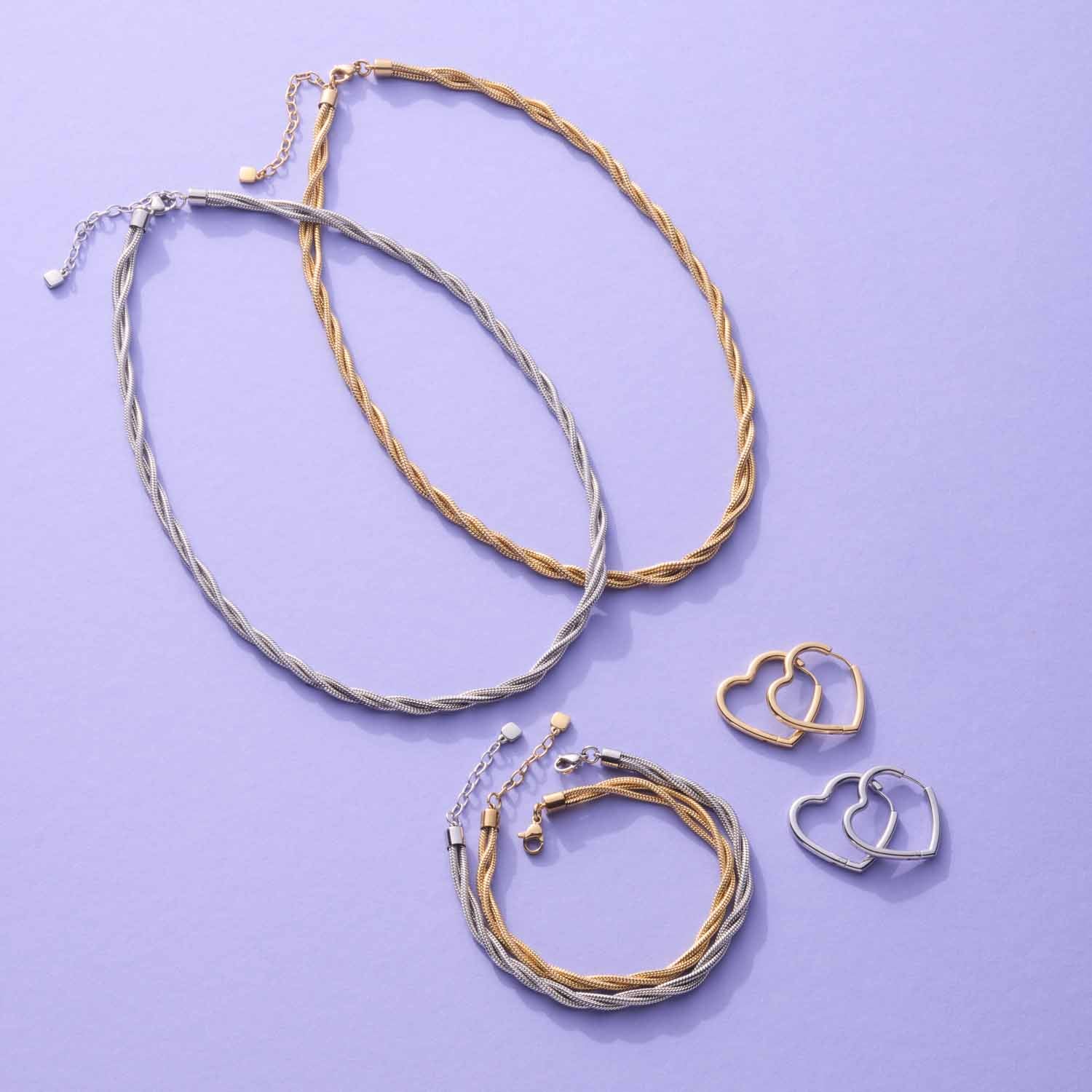 Creole LULU Schmuckset mit Ohringen und Ringen auf violettem Hintergrund