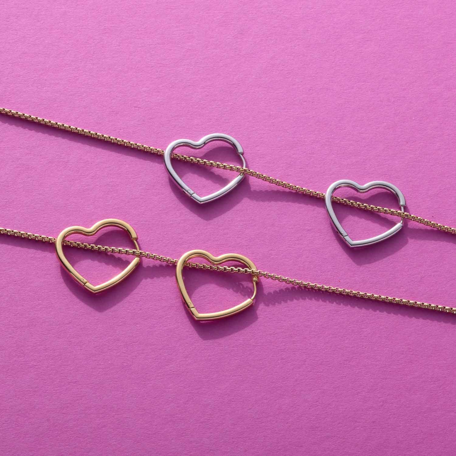 Creole LULU gold mit Herzanhängern auf rosa Hintergrund