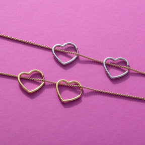 Creole LULU gold mit Herzanhängern auf rosa Hintergrund
