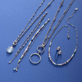 Schmuckkollektion aus Edelstahl auf blauem Hintergrund, Ketten, Ringe und Ohrringe