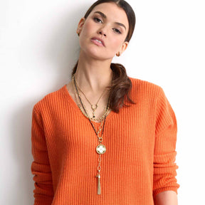 Frau traegt goldene Halskette TORY mit Anhaengern, orangenes Rippstrickshirt