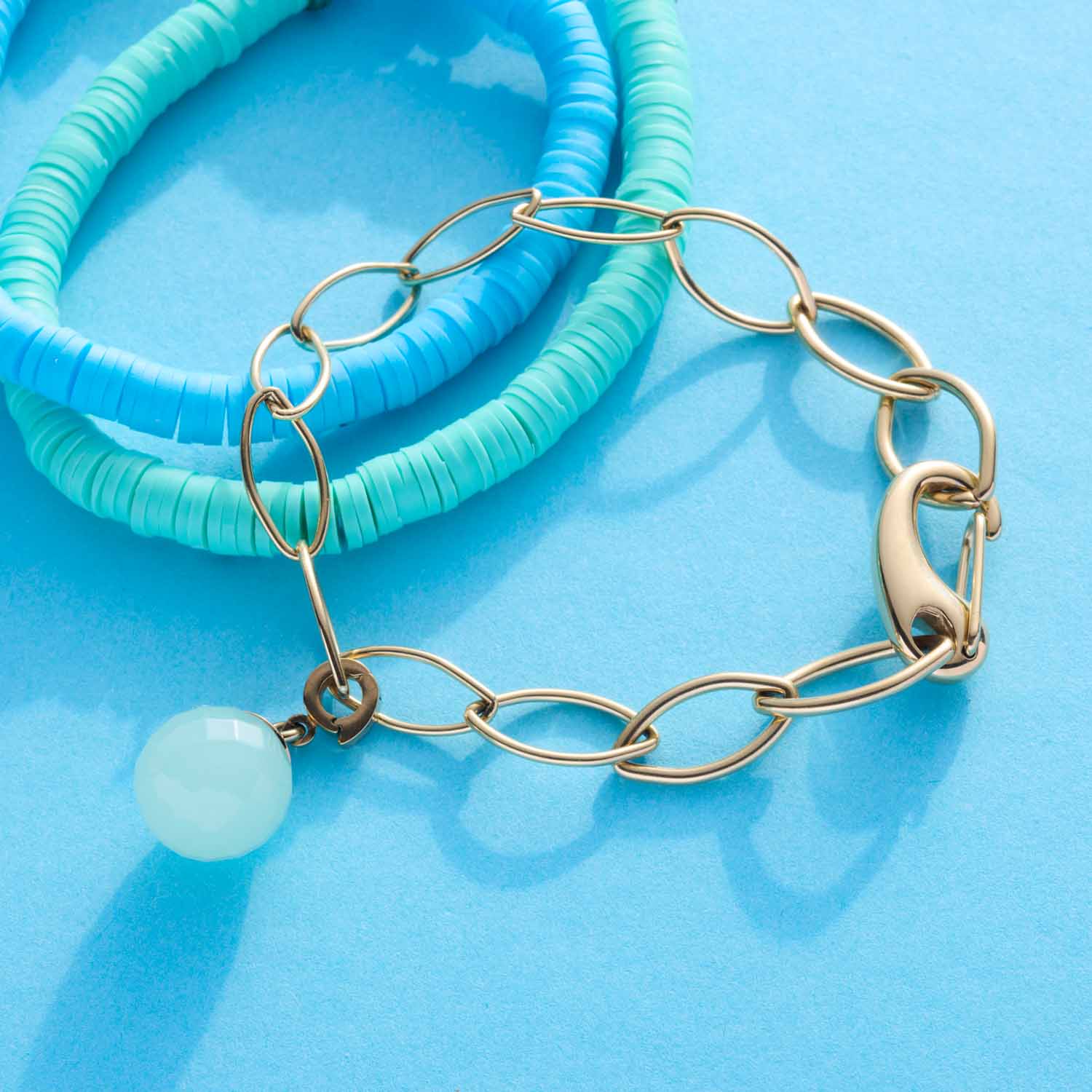 Armband TORY gold mit Kettengliedern und weißem Stein auf blauem Hintergrund