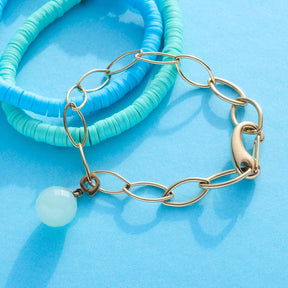 Armband TORY gold mit Kettengliedern und weißem Stein auf blauem Hintergrund