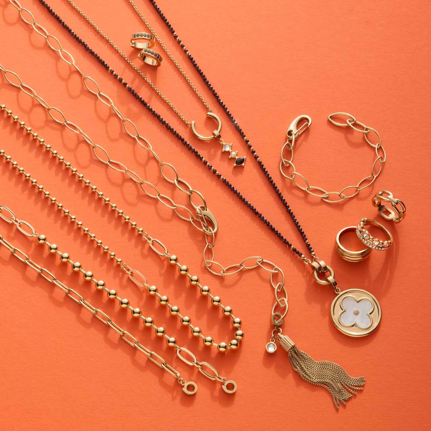 Armband DOTTY gold Clip & Mix mit Ketten und Ringen auf orangem Hintergrund