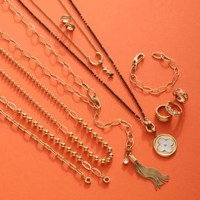Armband DOTTY gold Clip & Mix mit Ketten und Ringen auf orangem Hintergrund