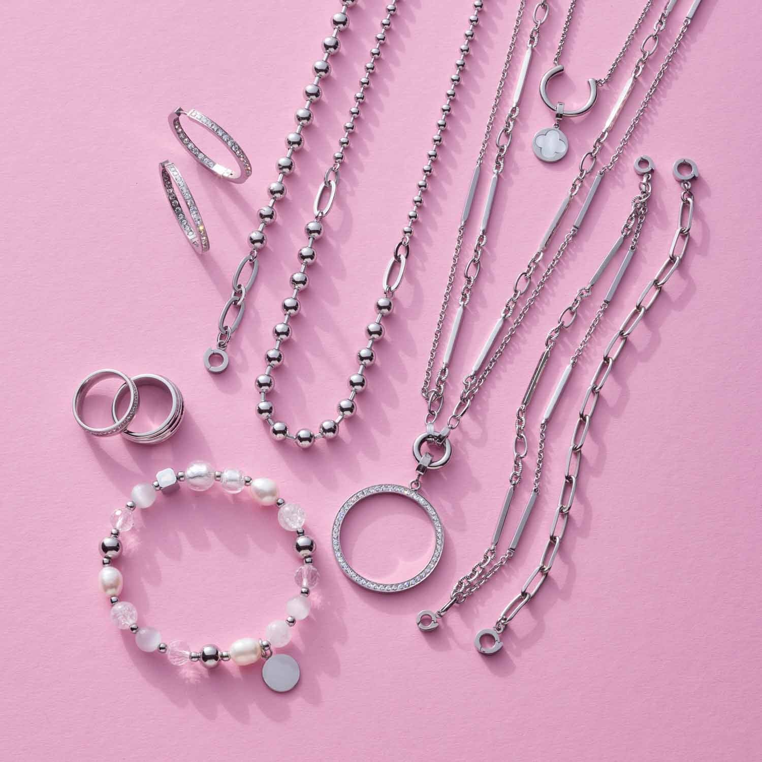 Armband GRACE Clip & Mix mit Ketten, Ringen und Perlenarmband auf rosa Hintergrund