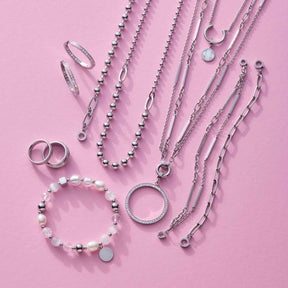 Armband GRACE Clip & Mix mit Ketten, Ringen und Perlenarmband auf rosa Hintergrund