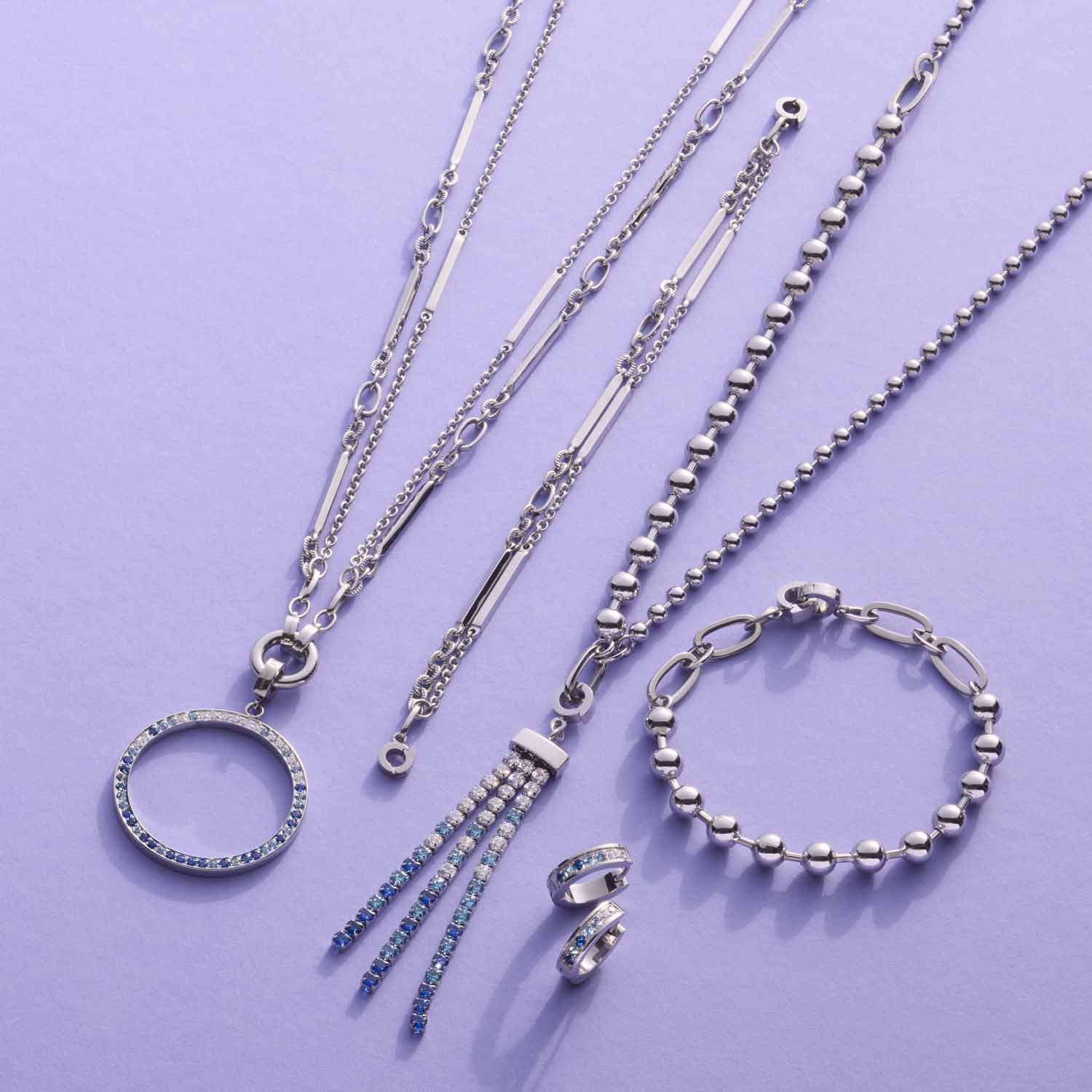 Silberne Halsketten und Armbänder aus der CLIP&MIX Serie auf violettem Hintergrund