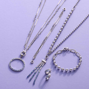 Silberne Halsketten und Armbänder aus der CLIP&MIX Serie auf violettem Hintergrund