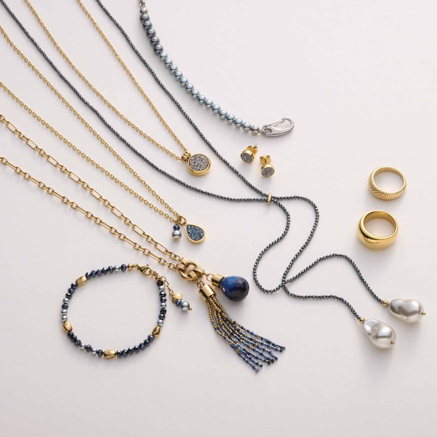 Halskette ODELLE mit Achat-Anhängern, Ringen und Ohrringen in Gold und Dunkelblau auf hellem Untergrund