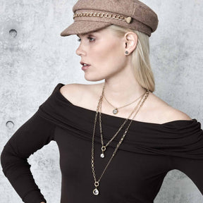 Frau trägt goldene Halskette ODELLE mit Achat-Anhängern, Beige-Mütze, schwarzes Oberteil