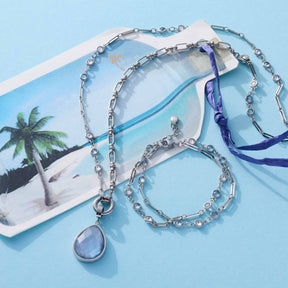 Armband VICKY mit Glasperlenkette und Anhänger auf blauem Hintergrund mit Strandmotiv