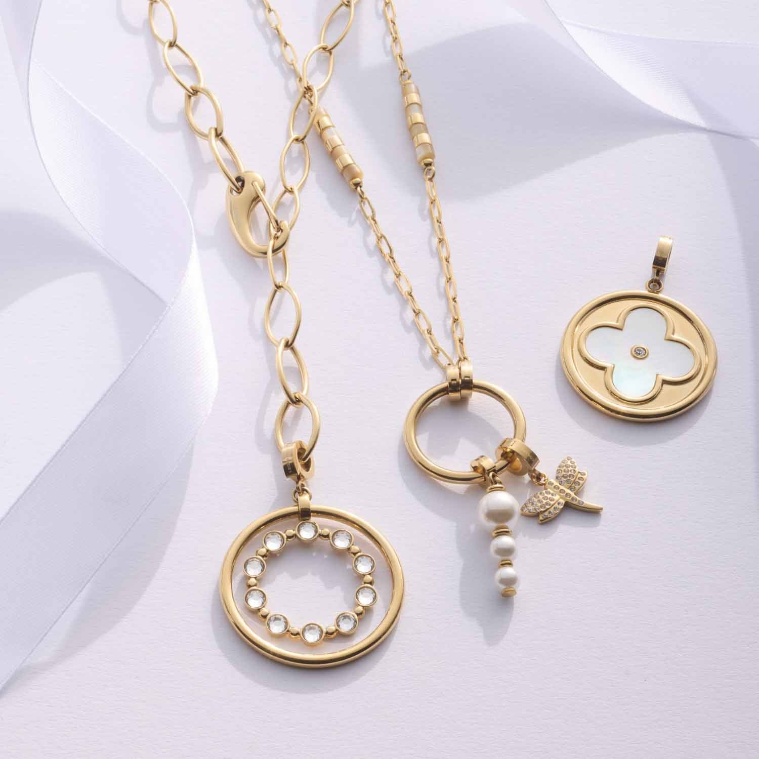 Drei goldene BOBBY Anhänger an Ketten auf weißem Hintergrund angeordnet