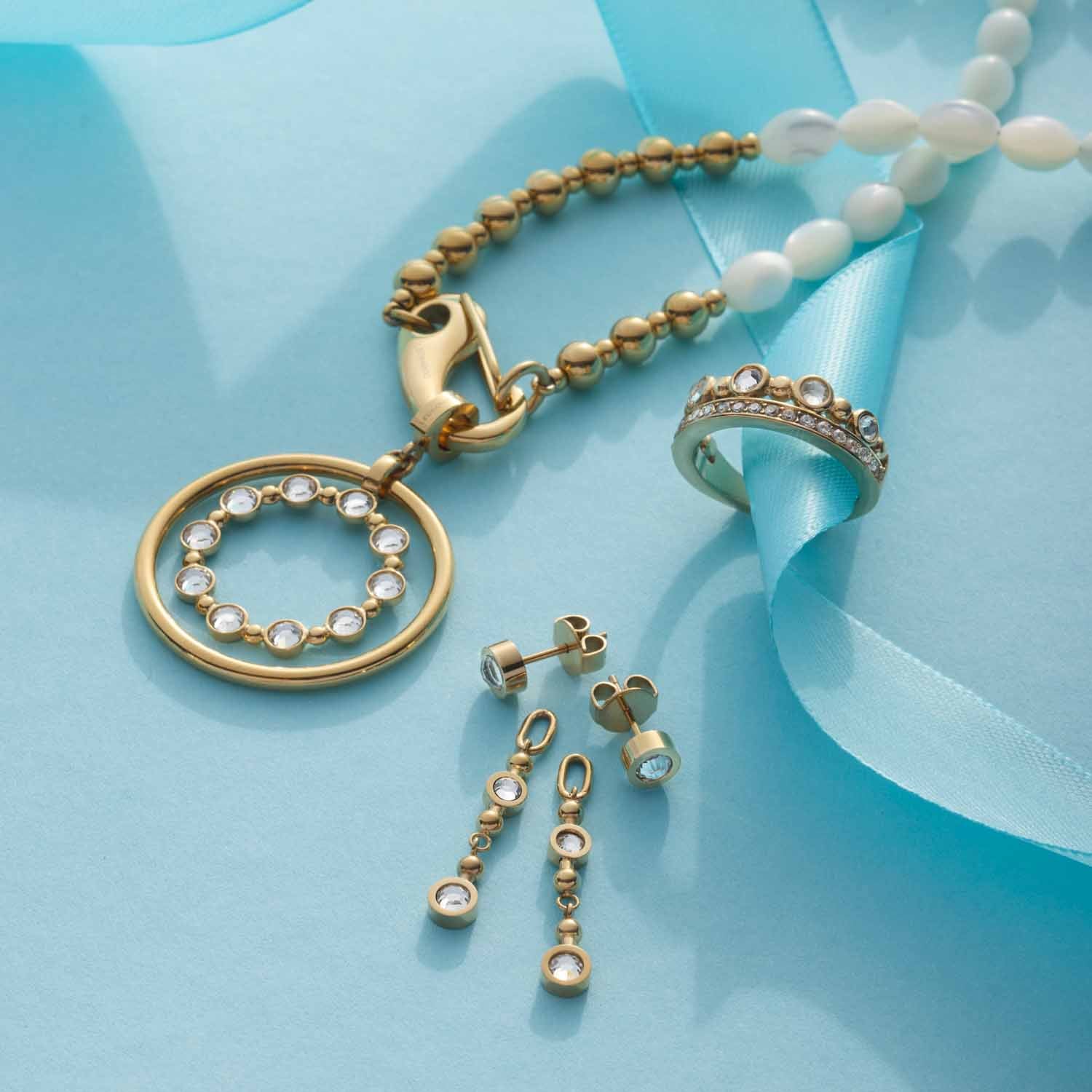 Anhänger BOBBY gold Clip & Mix mit Armband und Ohrhängern auf blauem Hintergrund