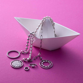 Anhänger BOBBY Clip & Mix mit Edelstahlketten und Ringen auf rosa Hintergrund in weißer Schale