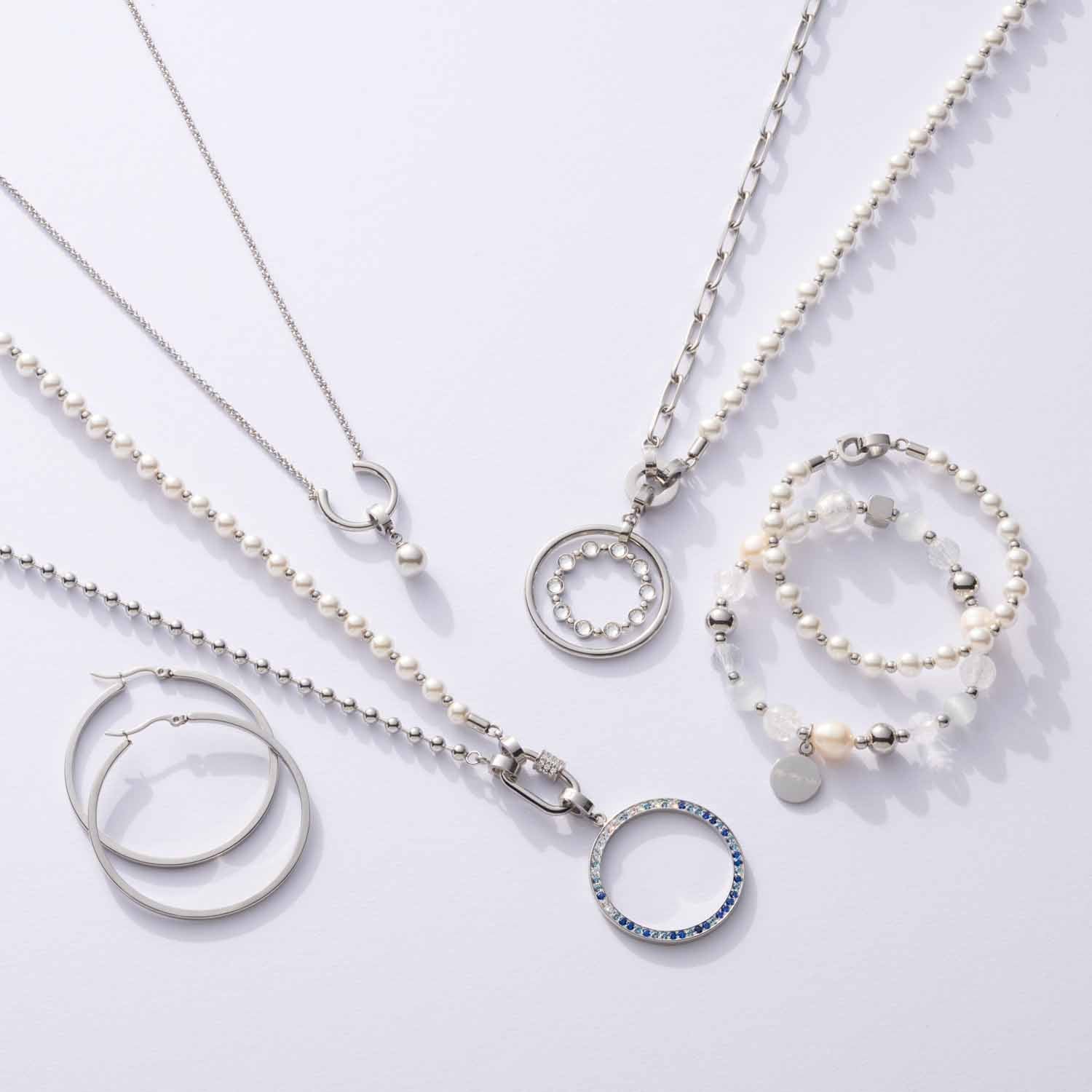 Schmuckkollektion mit Anhängern, Halsketten und Armbändern aus Edelstahl und Perlen auf weißem Hintergrund