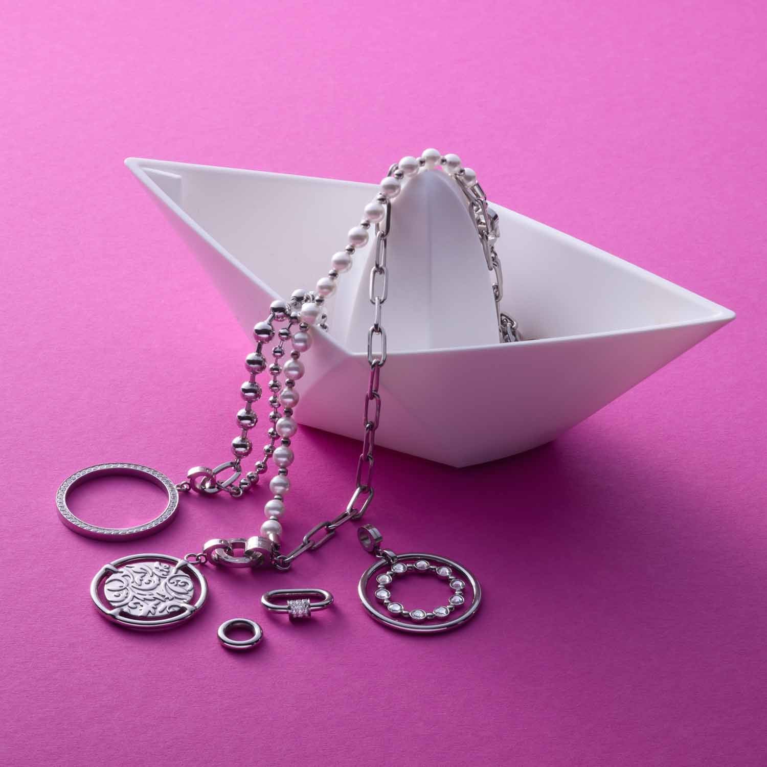 Silberne Anhänger TERRY Clip & Mix an Ketten in weißer Schale auf rosa Untergrund