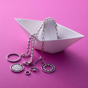 Silberne Anhänger TERRY Clip & Mix an Ketten in weißer Schale auf rosa Untergrund