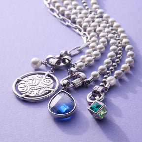 Anhänger TERRY Clip & Mix mit Perlenband und verschiedenen Charms auf violettem Hintergrund