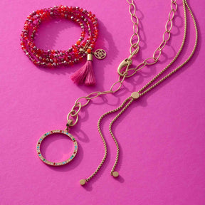 Anhänger CLARENCE gold Clip & Mix mit Ketten und Perlenarmband auf pink Hintergrund