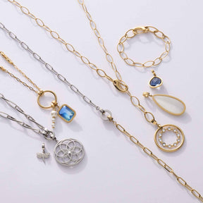Verschiedene Ketten und Armbänder in Gold und Silber mit Anhängern auf hellem Hintergrund