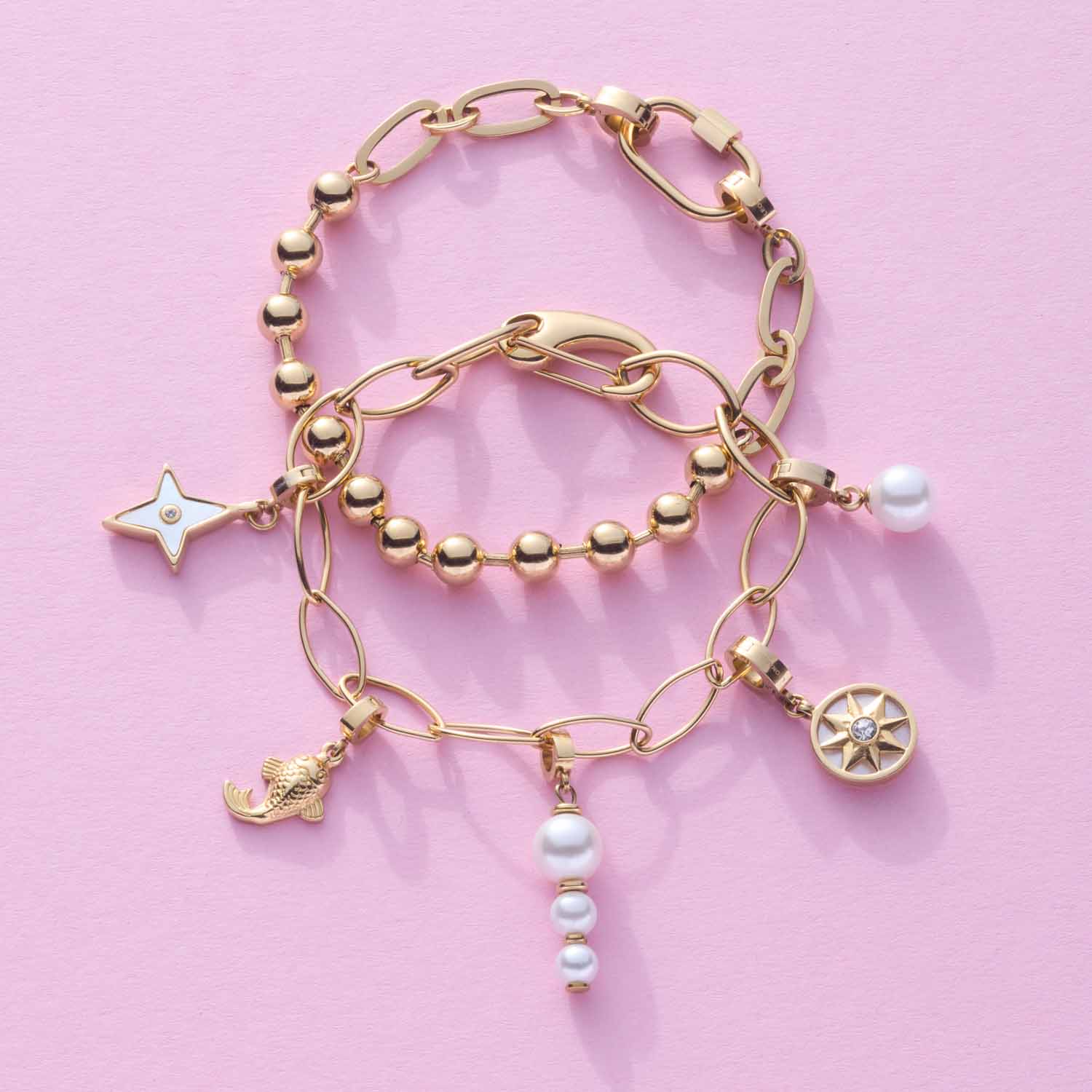 Drei goldene Clip&Mix Armbänder mit Perlen, Sternen- und Zitronencharm auf rosa Hintergrund