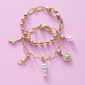 Drei goldene Clip&Mix Armbänder mit Perlen, Sternen- und Zitronencharm auf rosa Hintergrund