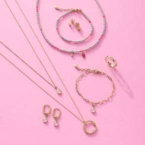 Schmuckkollektion auf rosa Hintergrund, Ohrhänger ROSY gold CIAO mit Glasperlchen, Ketten und Armbänder
