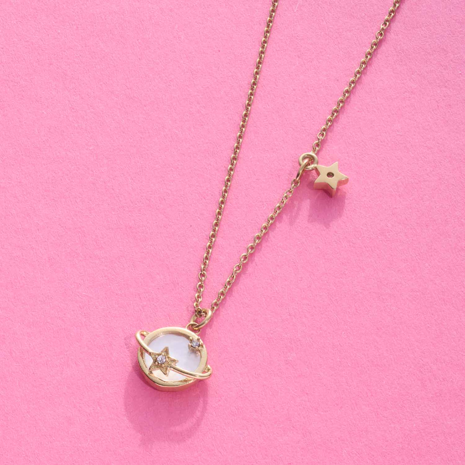 Halskette SATTELITE gold mit Stern-Anhänger auf rosa Hintergrund