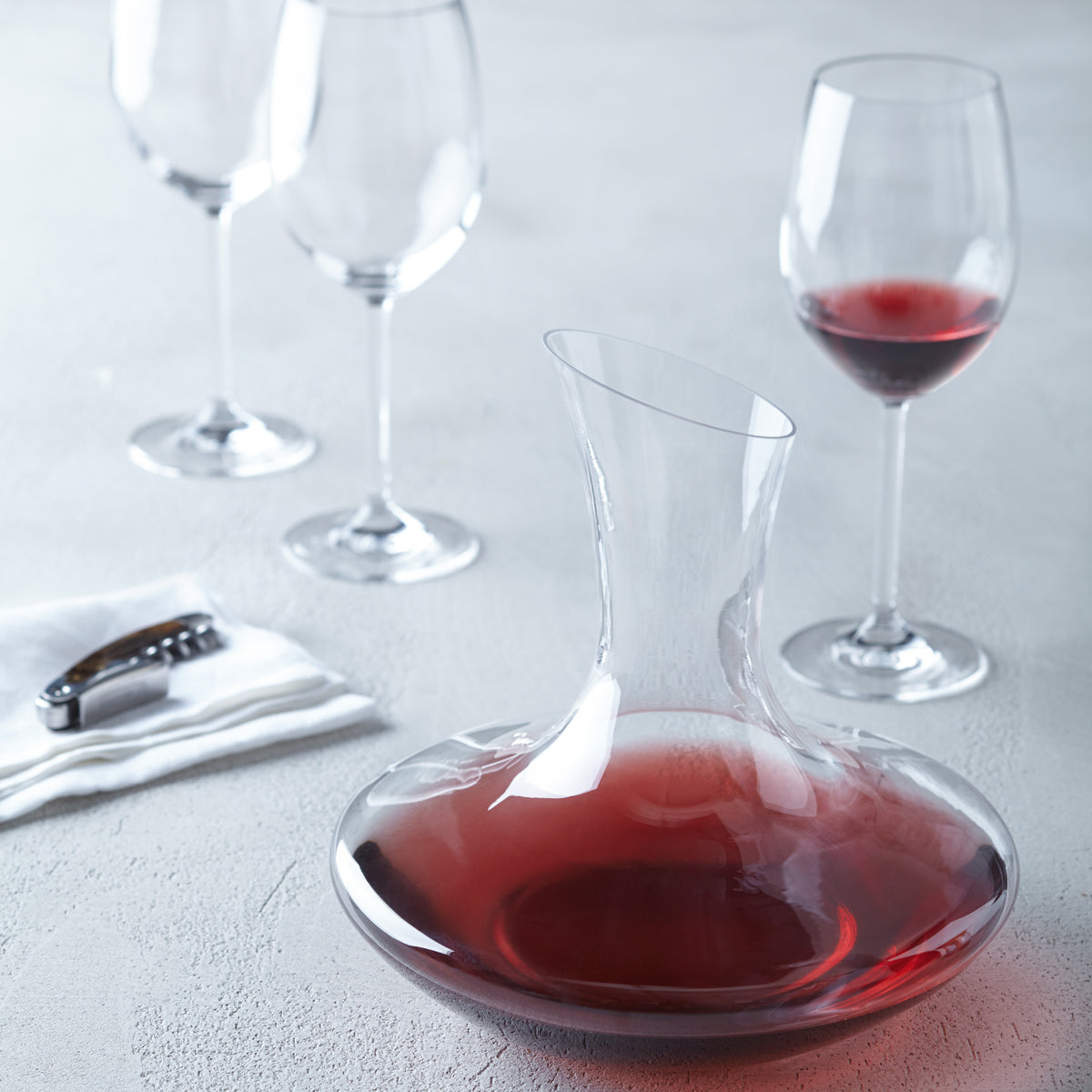 Dekanter DAILY mit Rotwein auf gedecktem Tisch mit Weingläsern