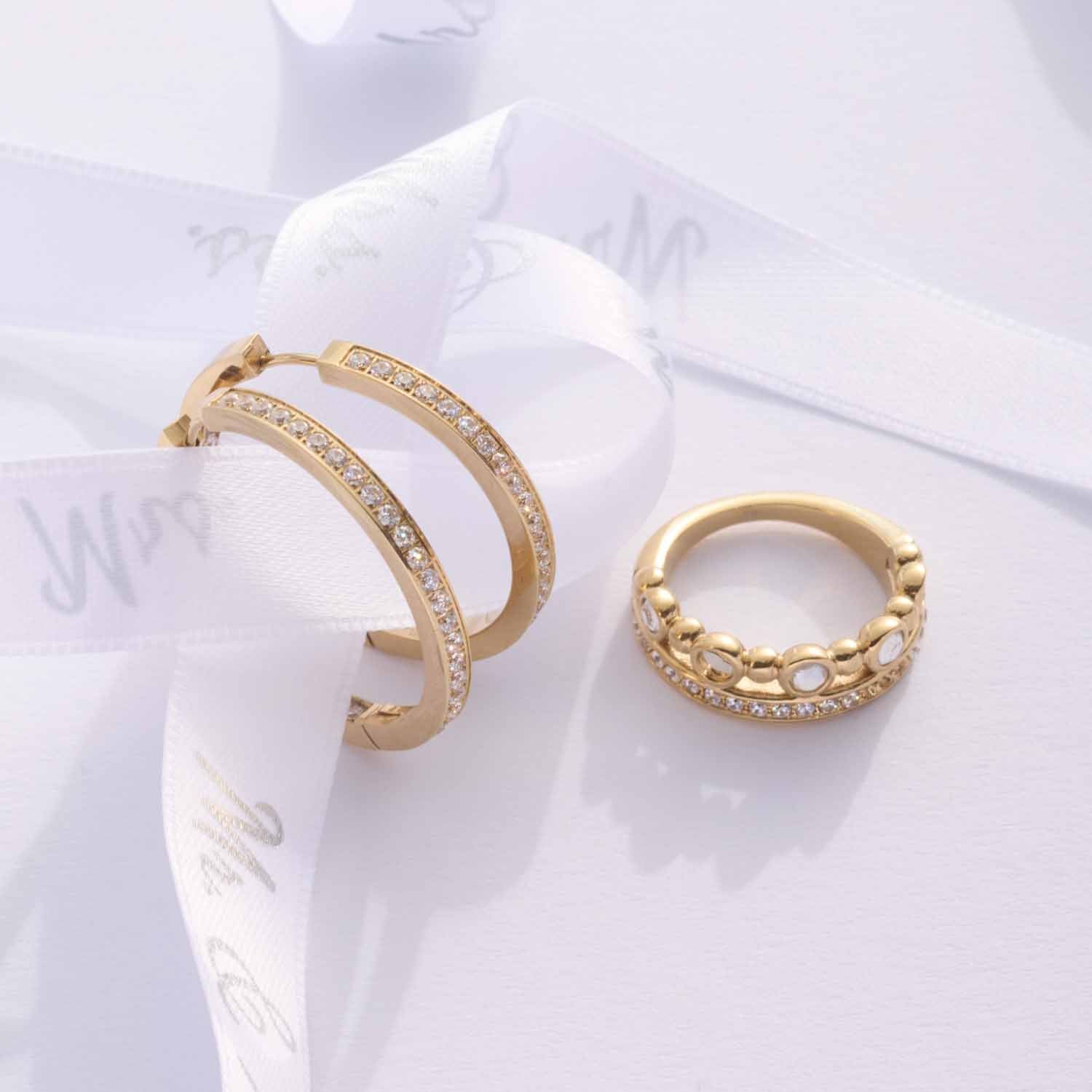 Ring BOBBY 19 gold mit Creolen und weißem Stoffband auf Oberfläche
