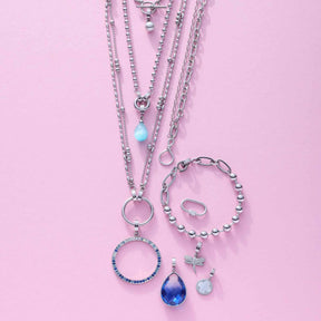 Silbernes Schmuckset mit Armbändern, Halsketten und Anhängern auf rosa Hintergrund