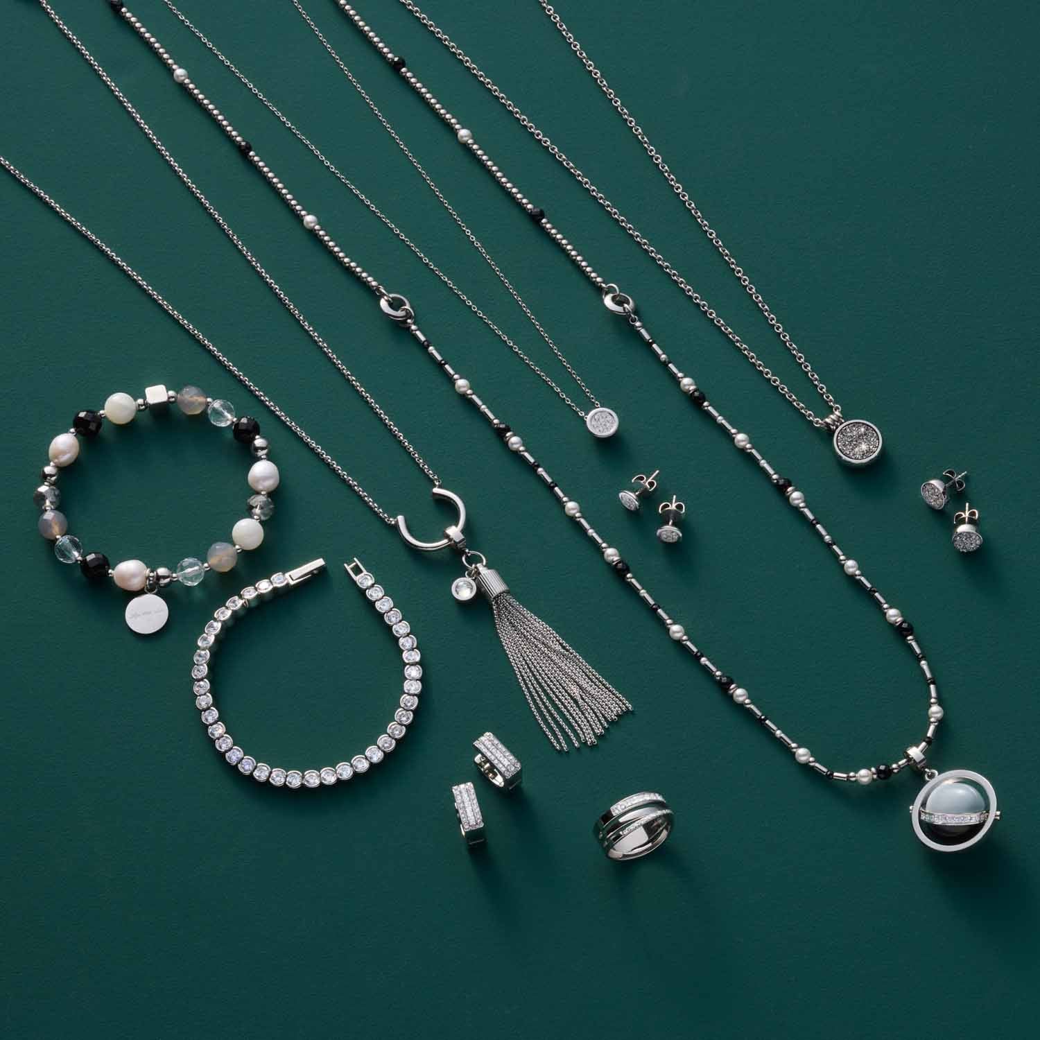 Schmuckkollektion mit Armbändern, Ketten und Ohrringen auf grünem Hintergrund