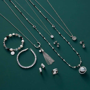 Schmuckkollektion mit Armbändern, Ketten und Ohrringen auf grünem Hintergrund
