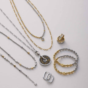 Schmuckkollektion mit Halsketten, Anhängern und Armbändern in Gold und Silber auf neutralem Hintergrund