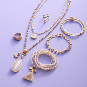 Schmuckkollektion aus gold mit Ringen, Ketten, Armbändern und Ohrringen auf violettem Hintergrund