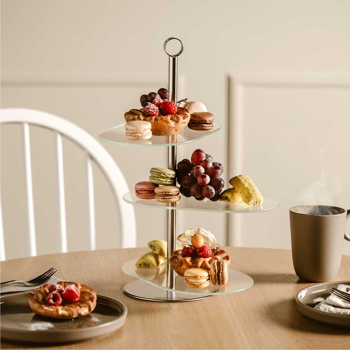 Etagere CENA silber mit Gebäck, Früchten und Macarons auf gedecktem Tisch