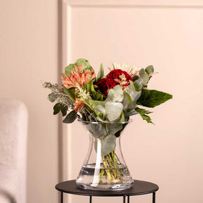 Vase GIA mit Schnittblumen auf schwarzem Tisch vor Wand