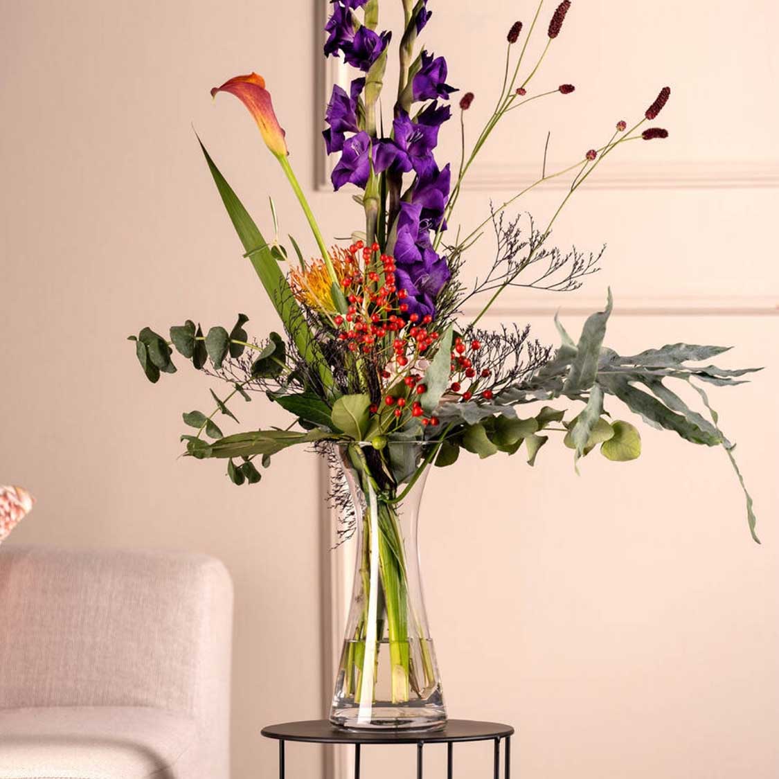 Vase GIA mit buntem Blumenstrauß in Wohnraum neben Sessel