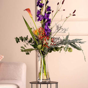 Vase GIA mit buntem Blumenstrauß in Wohnraum neben Sessel