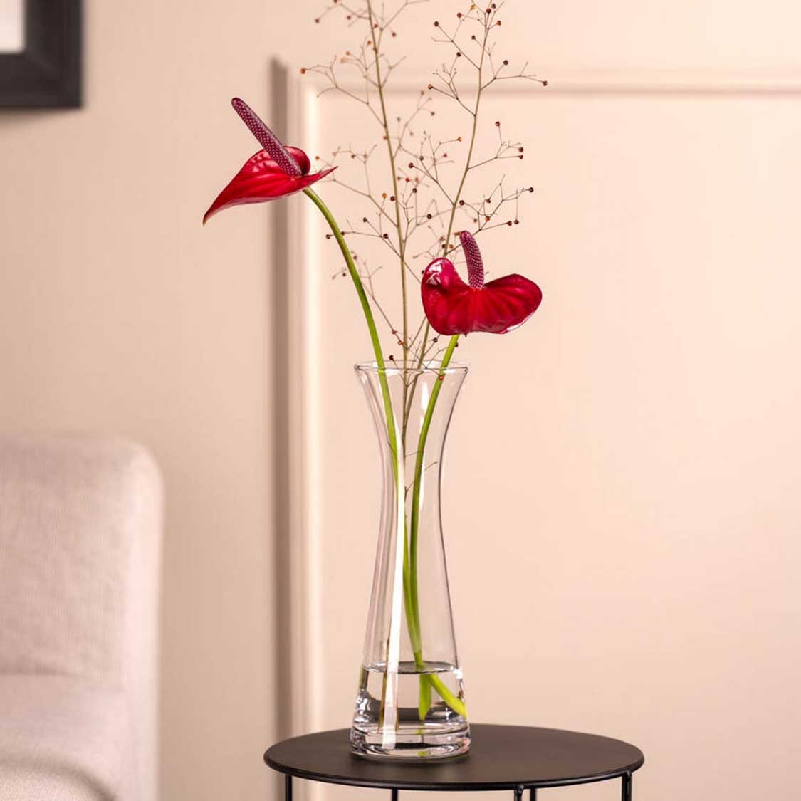 Solifleurvase GIA mit roten Blüten und Gräsern in Wohnraum auf Tisch