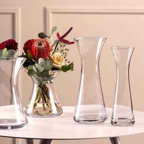 Solifleurvase GIA mit Blumenarrangement auf weißem Tisch, daneben leere Glasvasen
