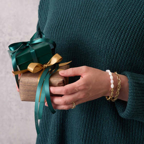 Frau mit Armband SINA gold und Geschenk in grüner Verpackung