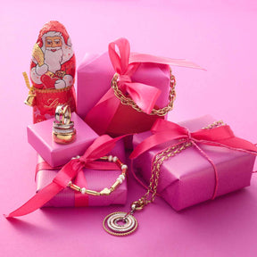 Armband SINA gold mit Geschenkboxen und Weihnachtsdeko auf rosa Untergrund